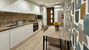 A modern kitchen with white cabinets, a wooden countertop, and a dining area with a table and chairs.