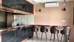 A modern kitchen with a marble countertop, a built-in stove, and a bar area with four stools. - Acuotel Inn Minakshi (Indore)