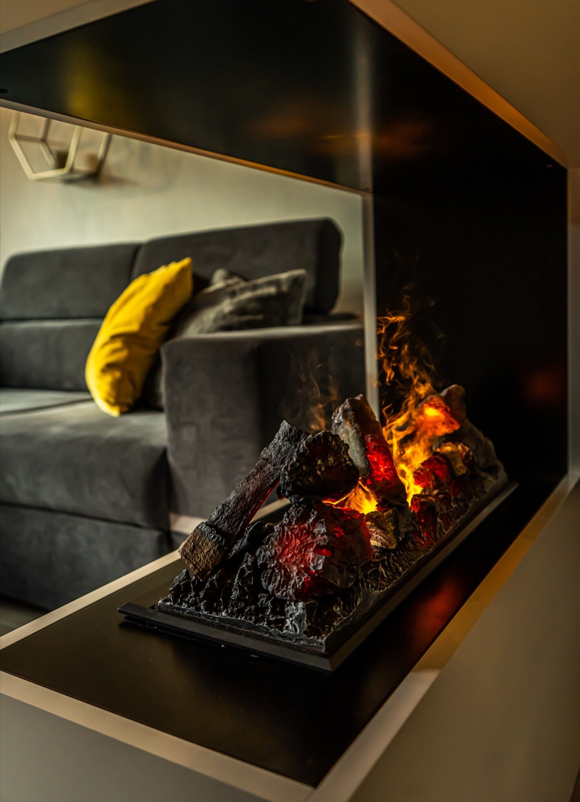 A modern living room with a fireplace, a sofa, and a yellow pillow.