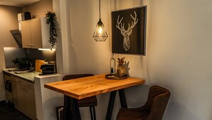 A modern kitchen with a wooden table, two bar stools, a hanging light, and a wall-mounted deer head artwork. - Apartment 'Mellies' with Private Terrace, Garden and Wi-Fi (Willingen (Upland))