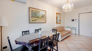Spiseplads med bord, stole, lysekrone, et maleri og en sofa.