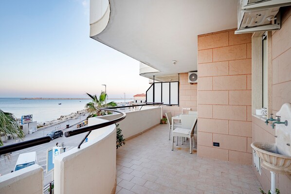 Un balcon avec vue sur la mer, un lavabo blanc et une chaise.