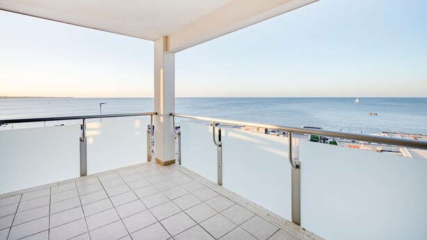 Ein Balkon mit Meerblick, einem Fliesenboden und einem Geländer.