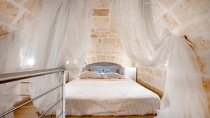 Ein Schlafzimmer mit einem Bett, Holzboden, Steinwand und Metallgeländer.