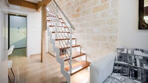 Eine Treppe mit Holzboden und Metallgeländern, eine Ziegelwand und ein gemustertes Sofa.
