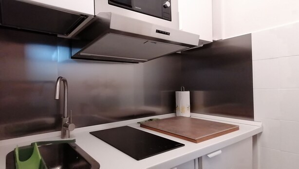 Une cuisine moderne dotée d’appareils électroménagers en acier inoxydable, d’un four encastré et d’un plan de travail comprenant une planche à découper et une tablette.