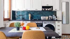A modern kitchen with white cabinets, a blue-tiled backsplash, and a dining area with a table set for two.