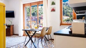 A compact kitchen with a dining area, a TV, and a view of a hillside.