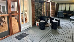 A covered outdoor area with a stone wall, a fireplace, and outdoor seating. - Christmas Creek Rainforest Retreat, ultimate nature filled group getaway. (Lamington)