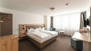 A hotel room with a large bed, a desk, a chair, and a small table. - TOP VCH Landschloss Korntal (Korntal-Munchigan)