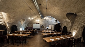 A spacious room with high ceilings and exposed brick walls, featuring multiple tables and chairs arranged for group meetings or presentations. - TOP VCH Landschloss Korntal (Korntal-Munchigan)