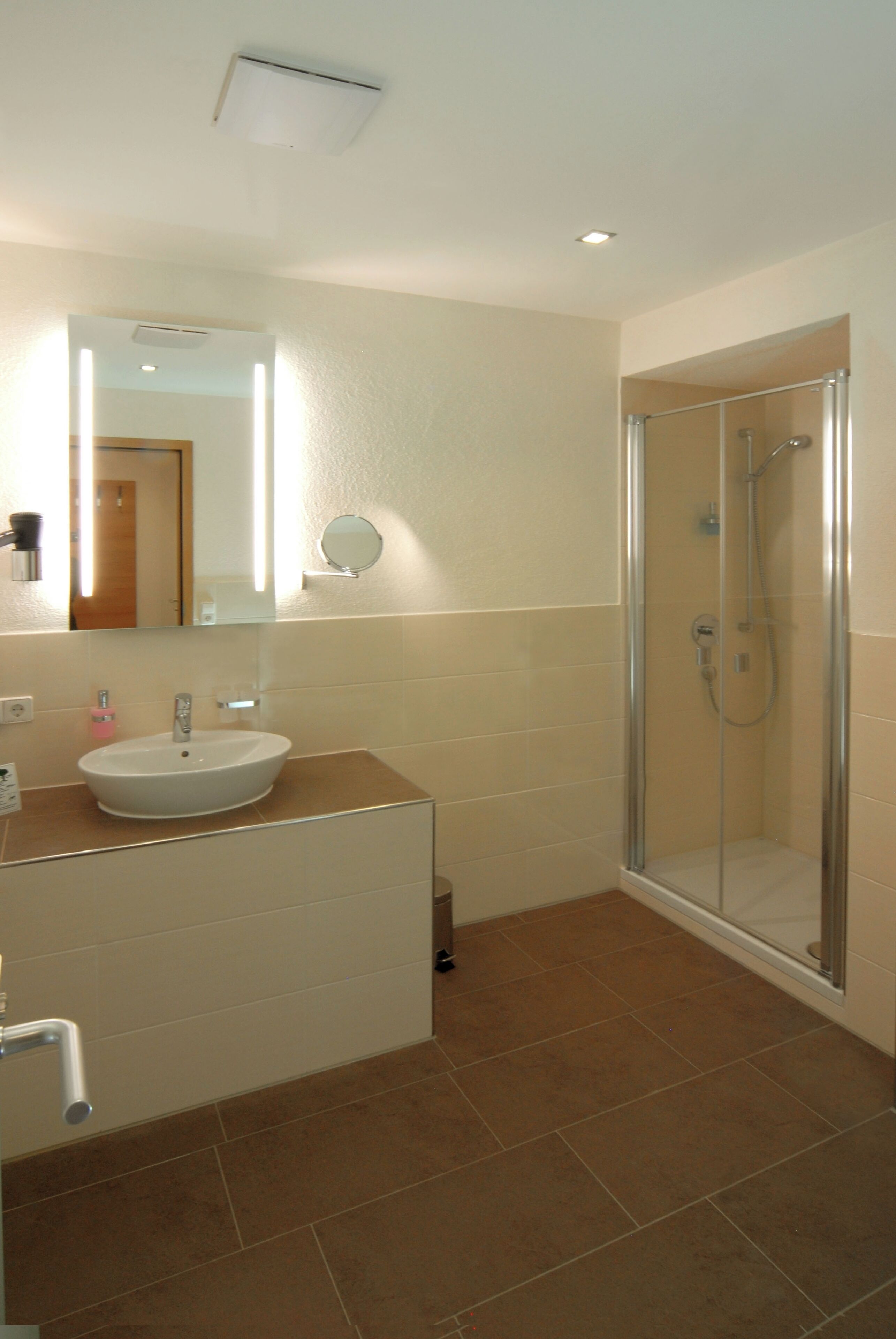 A bathroom with a sink, mirror, and shower.