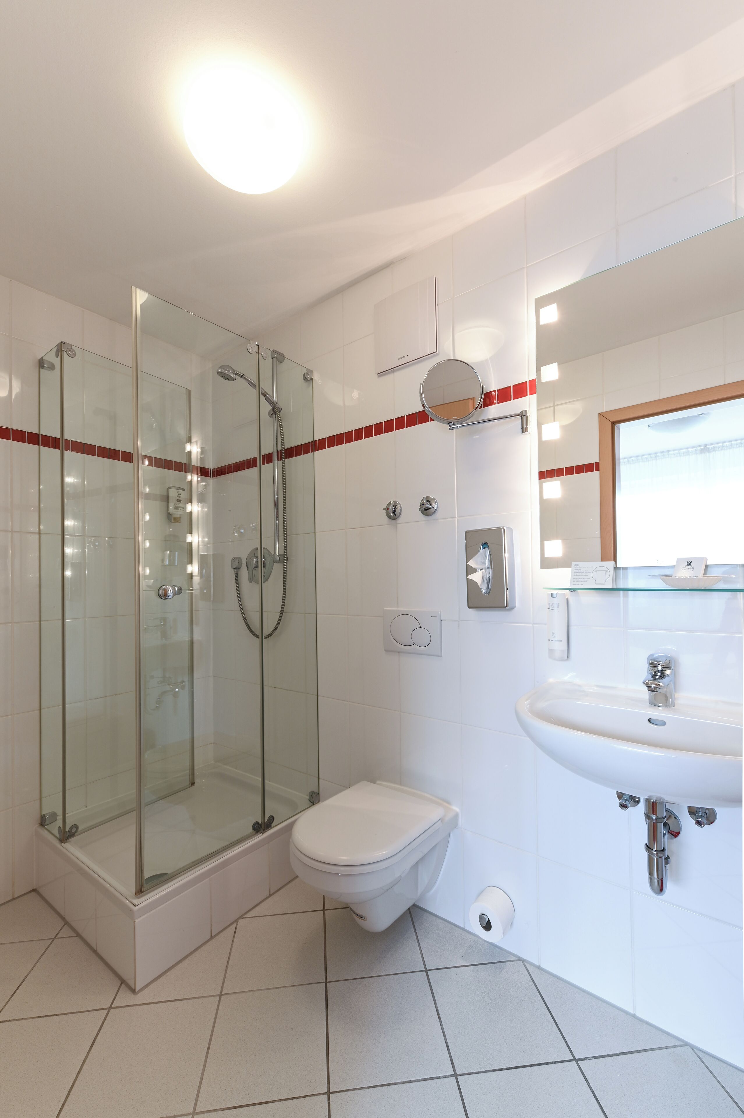 Ein modernes Badezimmer mit einer Duschkabine, einer Toilette und einem Waschbecken mit Spiegel darüber.