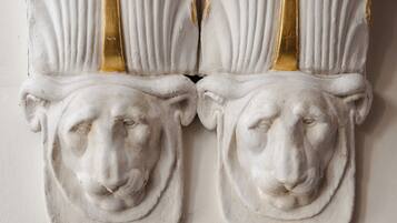 A white wall with two white, gold-framed decorative panels featuring a classical design.