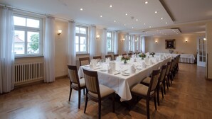 A long dining table set for a meal with chairs, large windows with curtains, and a radiator on the wall. - TOP VCH Landschloss Korntal (Korntal-Munchigan)