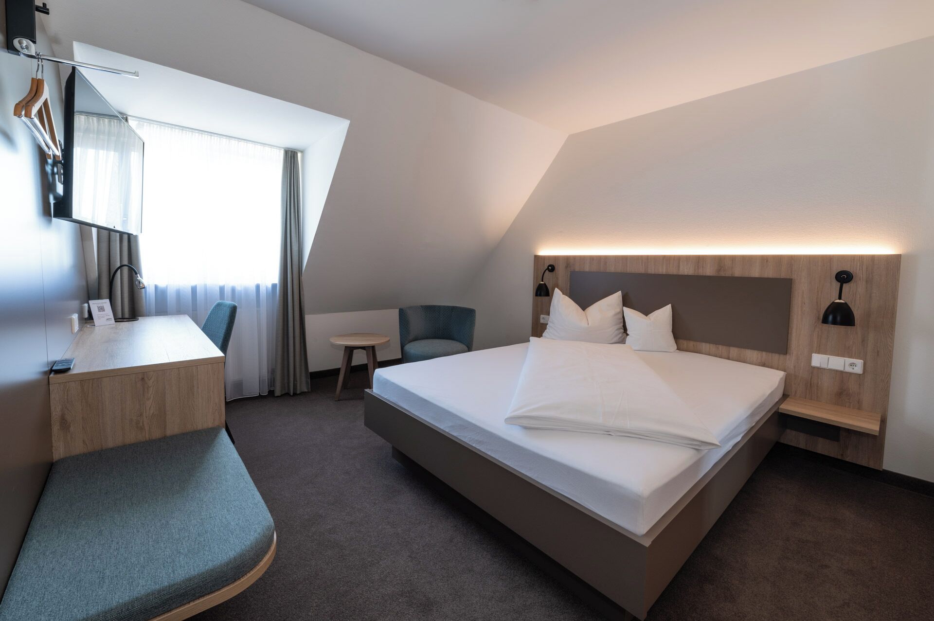 Una habitación de hotel moderna con una cama grande, un escritorio, una silla y una mesita.
