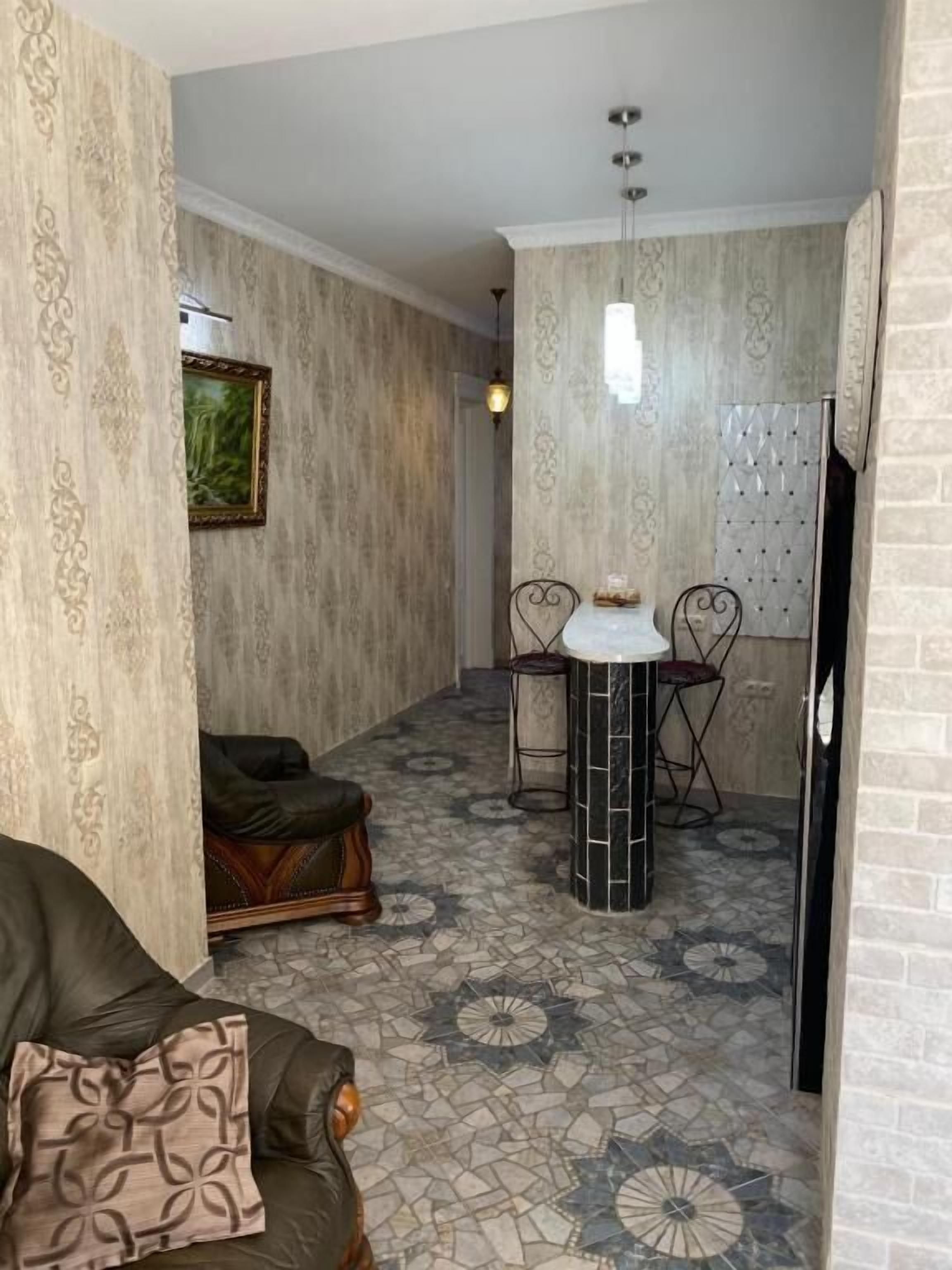 A cozy living area with a patterned floor, a sofa, and a dining table with chairs.