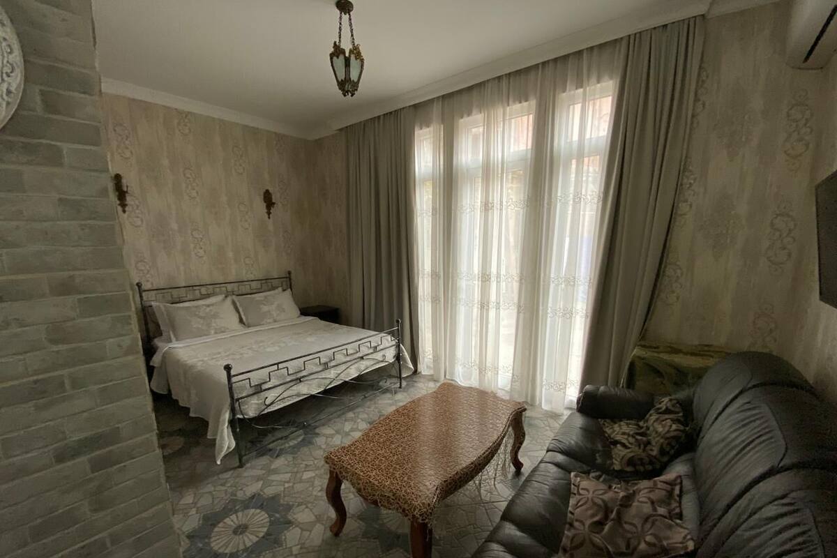 A bedroom with a bed, a leather sofa, and a patterned coffee table.