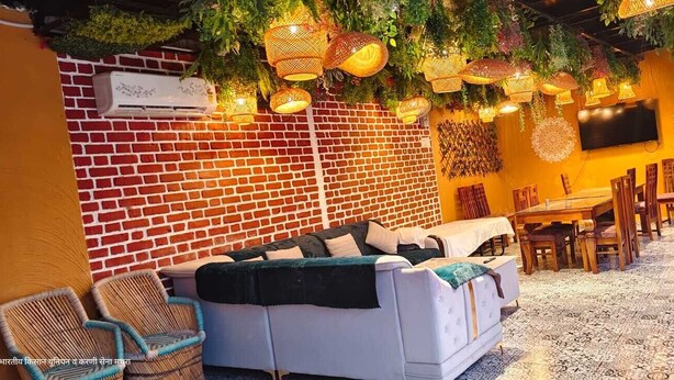 A cozy indoor space with a brick wall, a sofa, a dining table, and hanging lights.