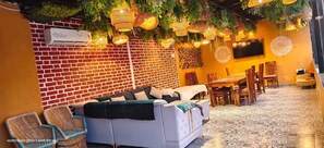 A cozy indoor space with a brick wall, a sofa, a dining table, and hanging lights. - samalia agro resort vrindavan (Chhata)