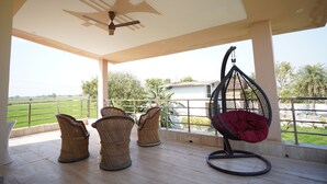 A covered outdoor area with wicker chairs, a hanging chair, and a ceiling fan.