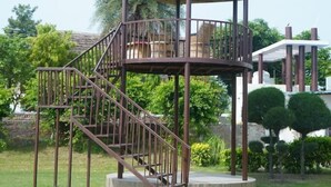 A gazebo with a thatched roof, a staircase, and a railing.