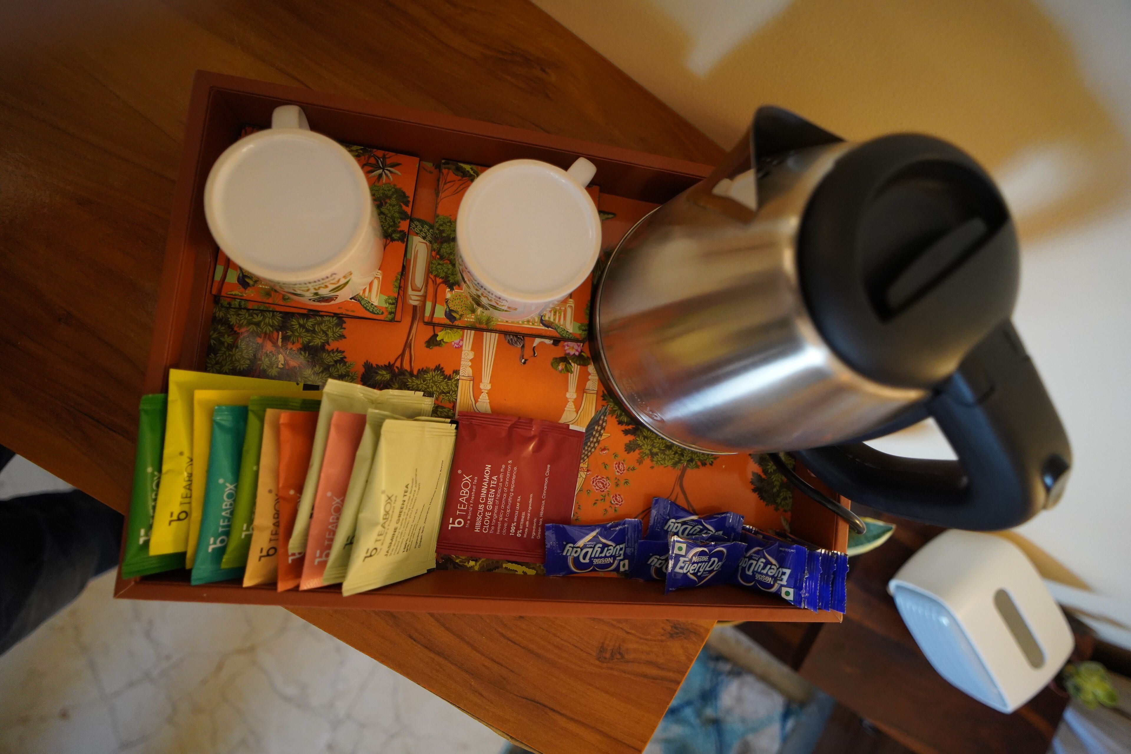 Egy tálca, rajta két fehér csészével, egy teáskannával és különböző teafajtákkal.