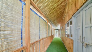 A corridor with a green carpet, wooden walls, and a bamboo ceiling.