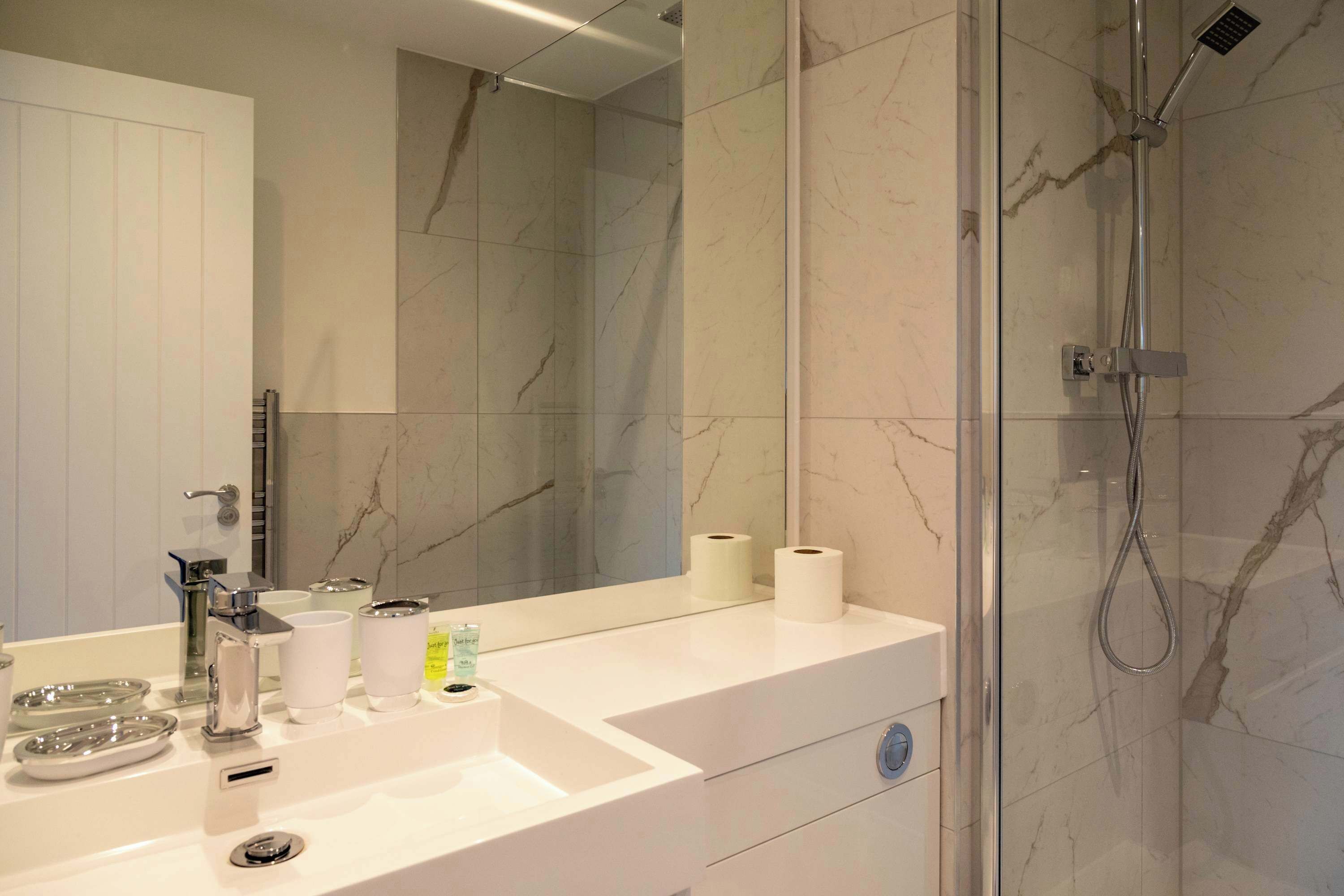 Een moderne badkamer met een wit wastafel, een spiegel en een douche met glazen wanden.