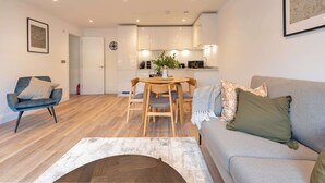 En moderne stue med en grå sofa, en blå lænestol og et træspisebord med stole.