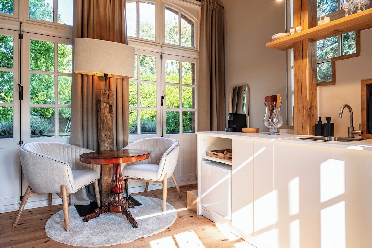 A modern kitchen with a central island, large windows, and a view of greenery.