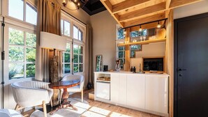 Une cuisine moderne avec des poutres en bois, un plan de travail blanc et une porte noire.