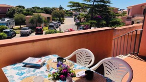 A balcony with a table set for two, featuring a book, a mug, and a small vase with flowers. - Three-room apartment Oleander 300 mt beach San Teodoro (San Teodoro)
