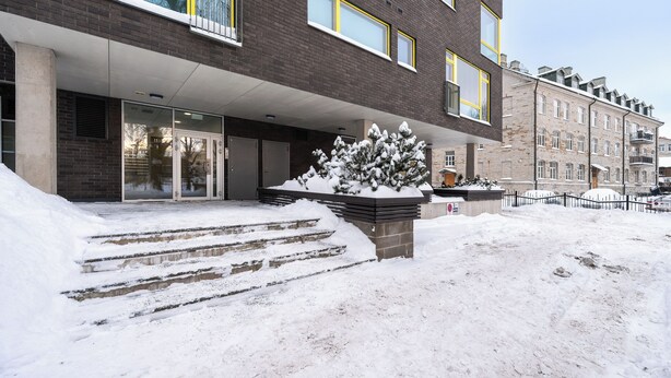 Ein modernes Gebäude mit Backsteinfassade, großen Fenstern und einem verschneiten Eingang.