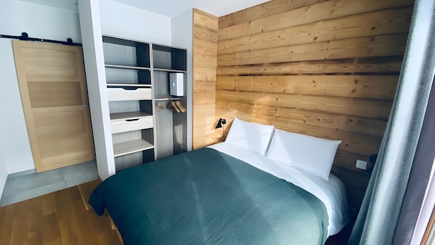 Un dormitorio con cama, armario y estantería empotrada.