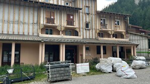 Un edificio de varios pisos con balcones, un camino de grava y materiales de construcción.