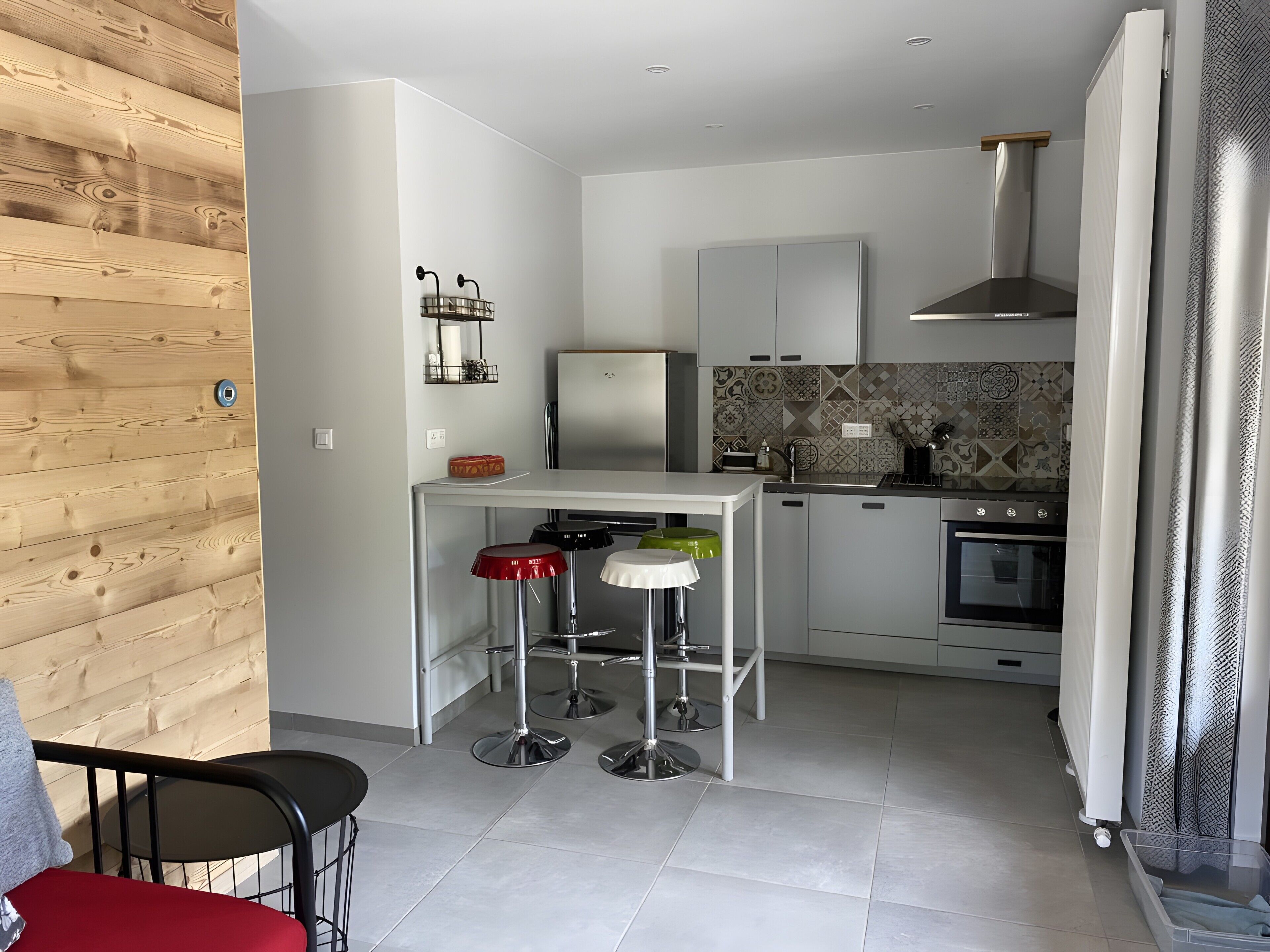 Une cuisine compacte équipée d’un réfrigérateur, d’une cuisinière et d’un petit coin repas avec des tabourets.