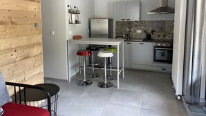 Una cocina compacta con refrigerador, estufa y un pequeño comedor con taburetes.