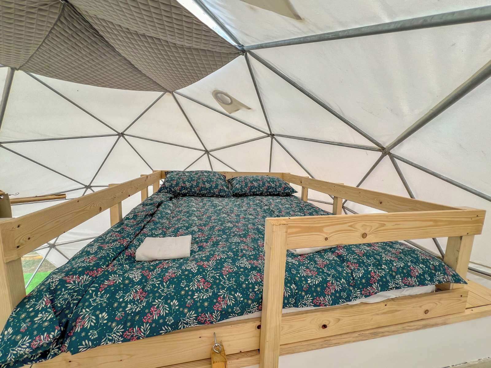 Een bed met een bloemenbed overtrek in een geodetische koepelstructuur.