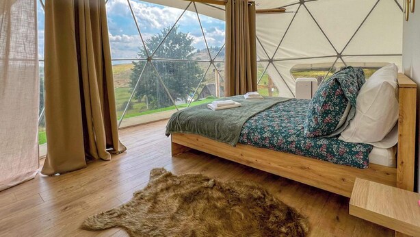 Una habitación acogedora con una cama, una mesita de noche de madera y una alfombra de piel.