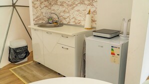 Una cocina compacta con salpicadero de mármol, un lavabo, un refrigerador pequeño y un cesto de basura.