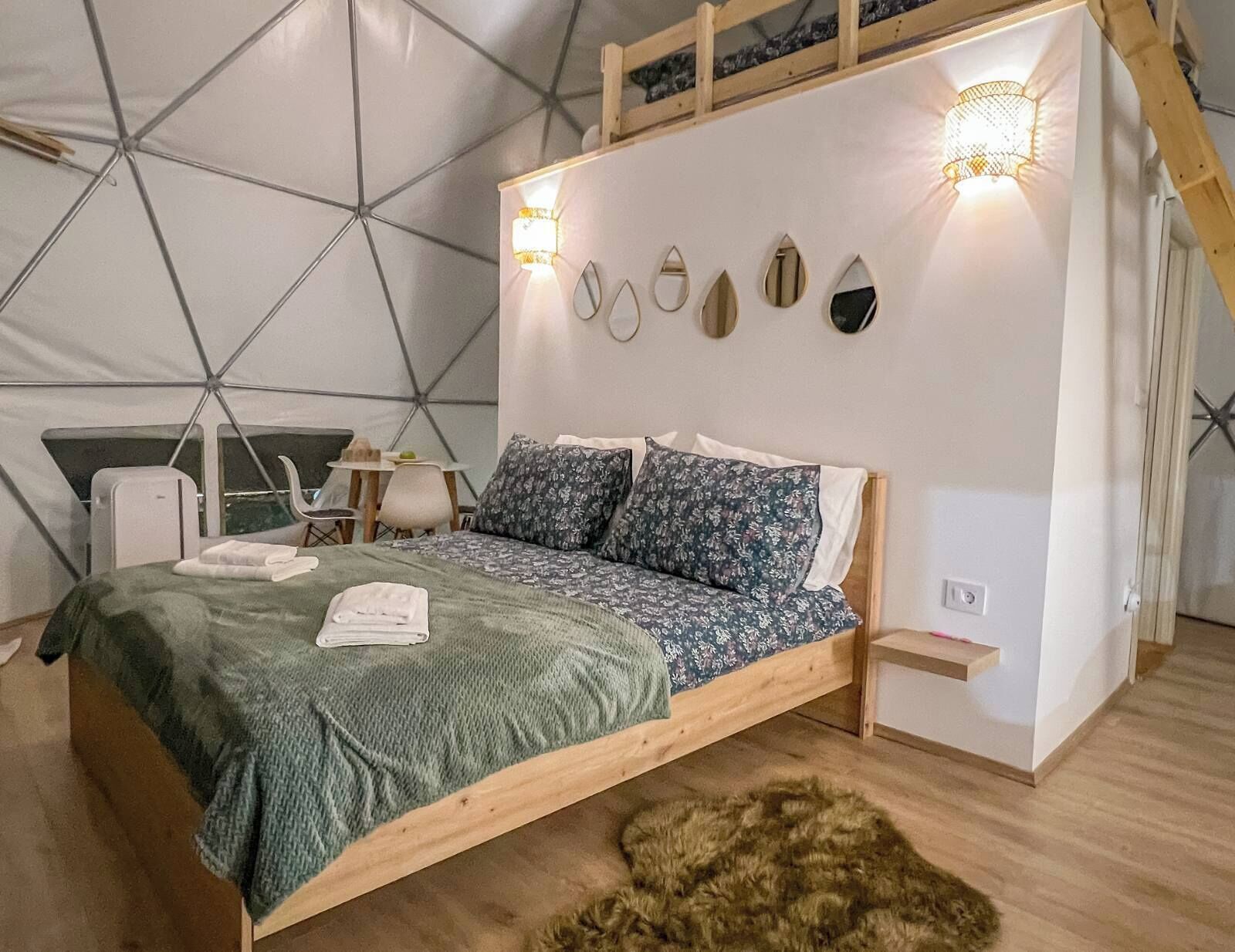 Une chambre confortable aménagée comme une tente, avec un lit, des oreillers, une petite table et une chaise.