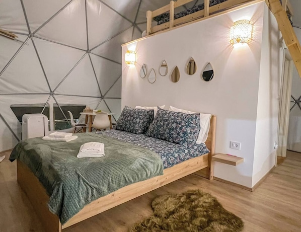 Un dormitorio tipo tienda de campaña con cama, almohadas, una mesita pequeña y una silla.