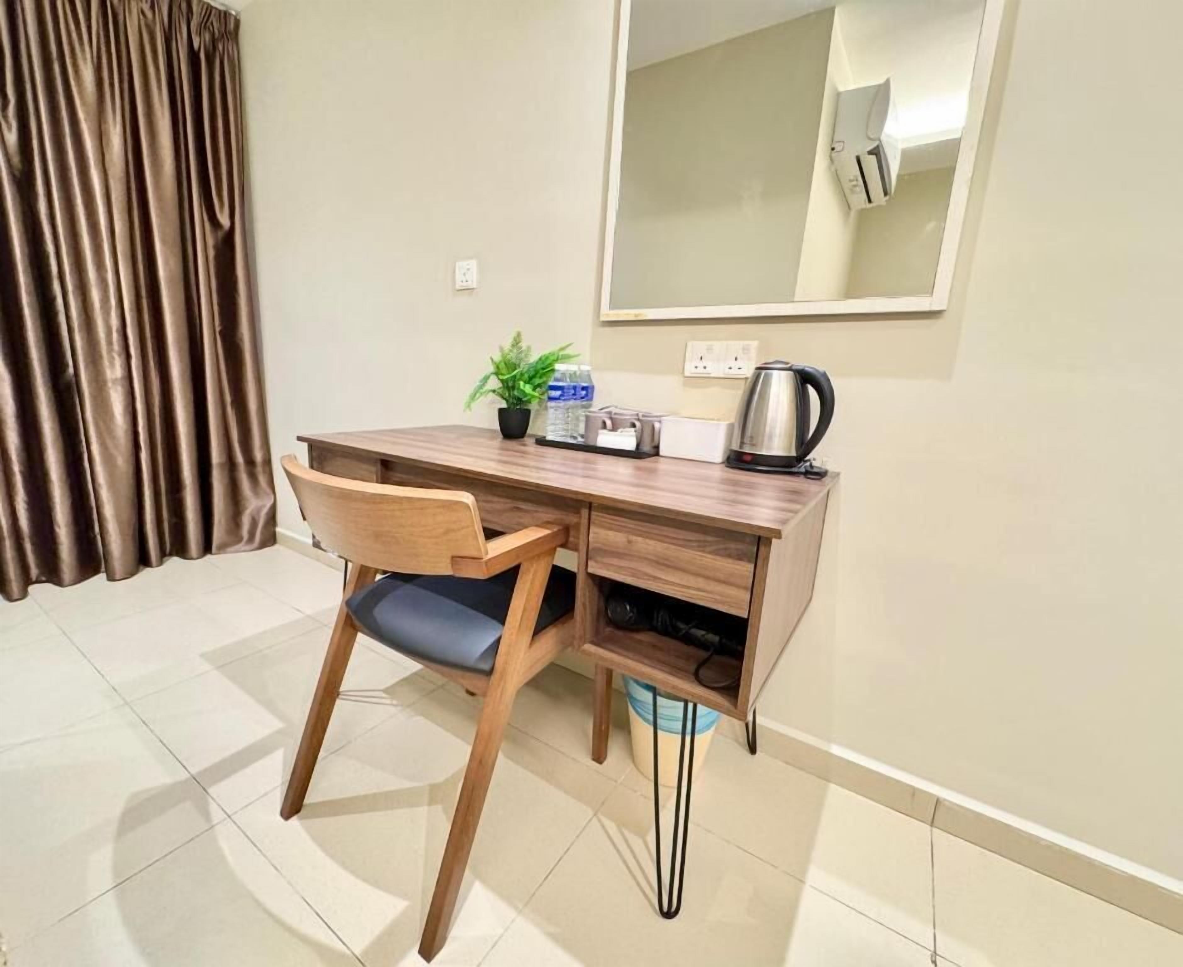 A small, neatly organized room with a wooden desk, a chair, a potted plant, a kettle, and a mirror on the wall.
