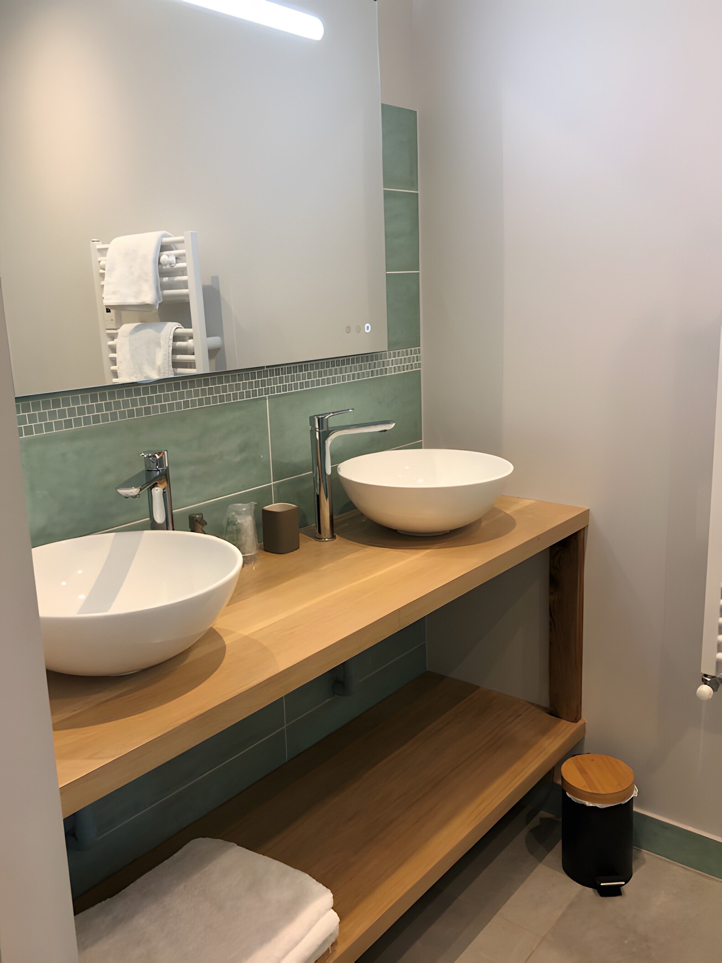 A modern bathroom with two sinks, a mirror, and a towel rack.