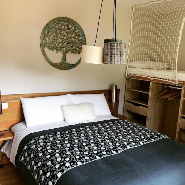 A bedroom with a bed, a hanging light, a wardrobe, and a wall decoration.