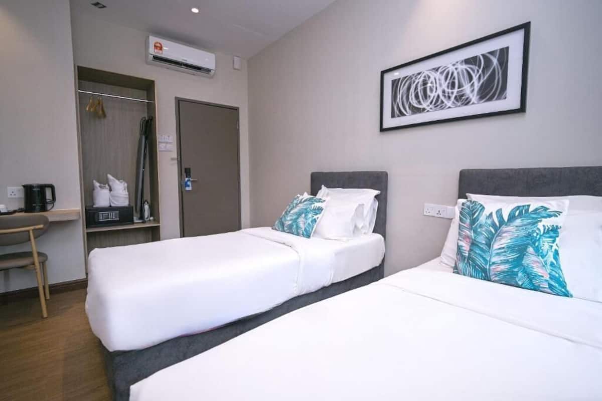 Une chambre d’hôtel avec deux lits, un bureau, une armoire et un appareil de climatisation.