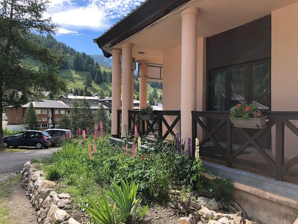 A hotel with a covered outdoor area, stone walls, and a variety of plants.
