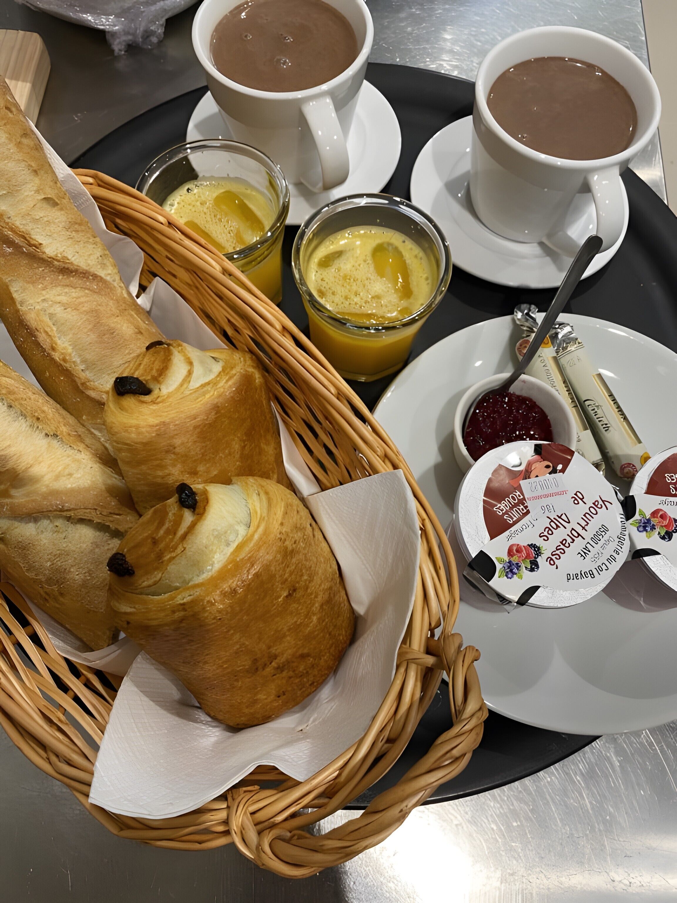 Ein Frühstücksbrett mit Croissants, Kaffee, Saft und einer kleinen Marmeladenschale.