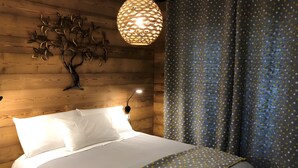 A bed with white bedding, a decorative wall piece, a hanging light fixture, and a curtain with a polka dot pattern. - Bed and Breakfast 'La Baïta De La Foux - Chambre 1' with Mountain View, Shared Terrace and Wi-Fi (La Foux d'Allos)